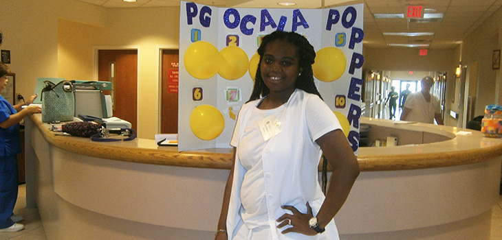smiling staff member in front of sign