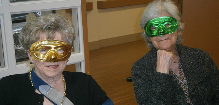 female residents with green and gold mardi gras masks
