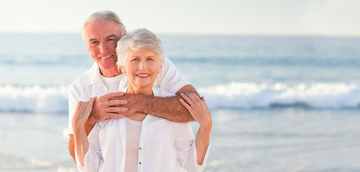couple on the beach, he has his arms around her