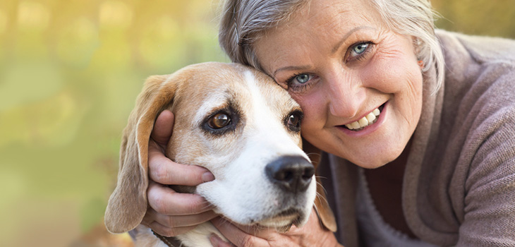 smiling woman with pretty blue eyes hugging a dog